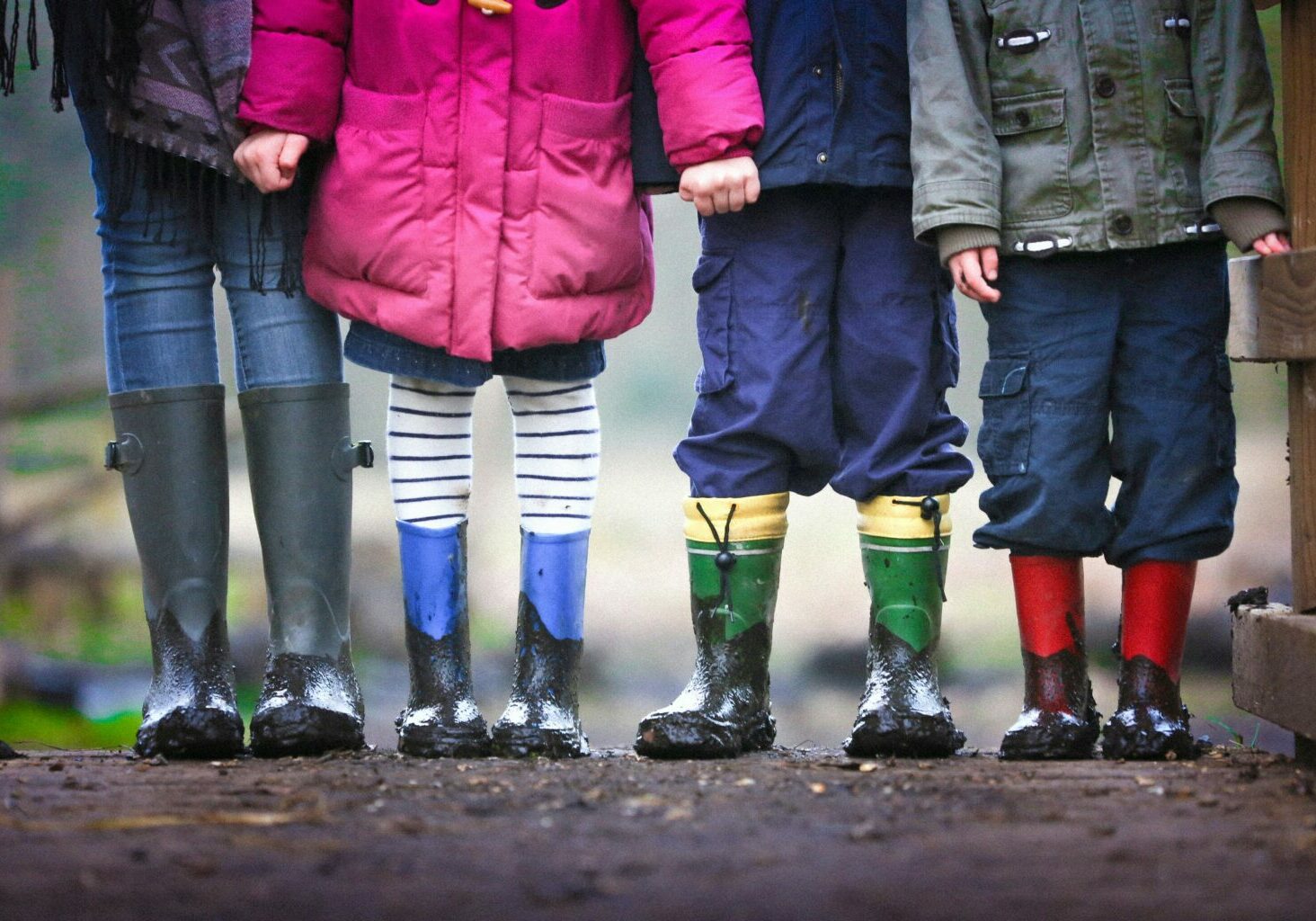 Children in raincoats and wellies holding hands